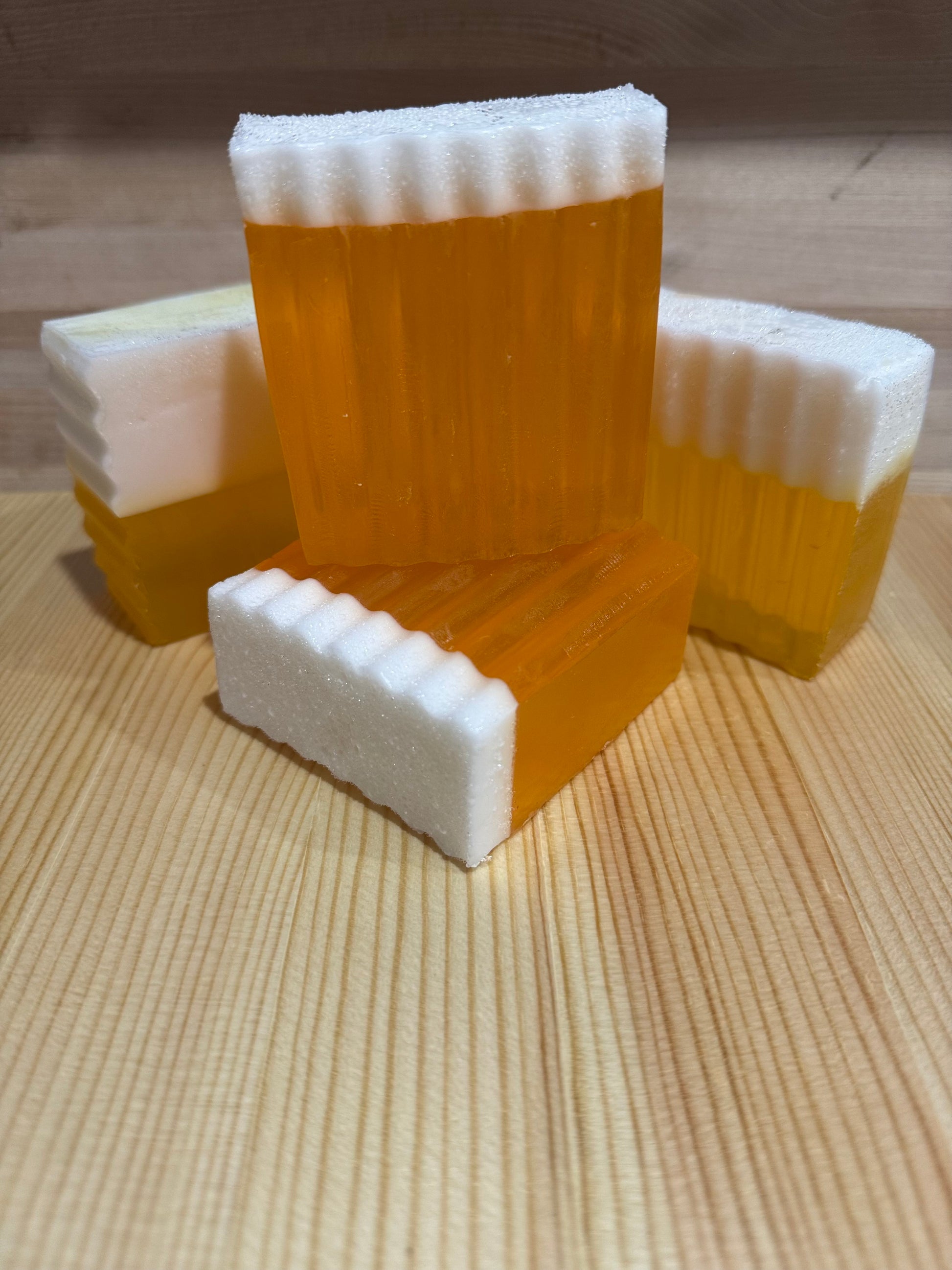 Close up of handmade orange and yellow glycerin soaps with a top layer of white goat milk