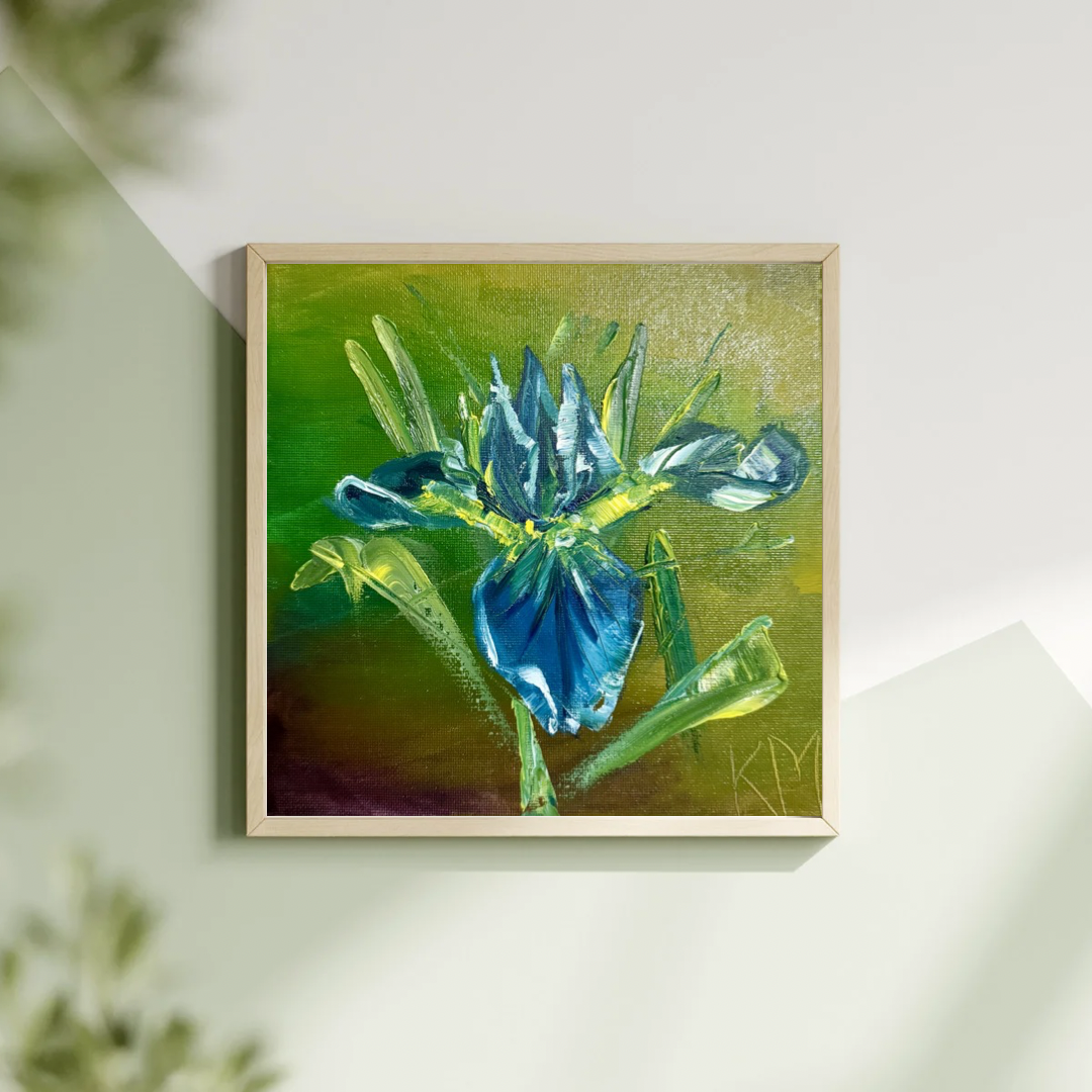 An oil painting of a blue iris on a small square 8”x8” canvas by Katya Montes Art displayed in a frame on a wall
