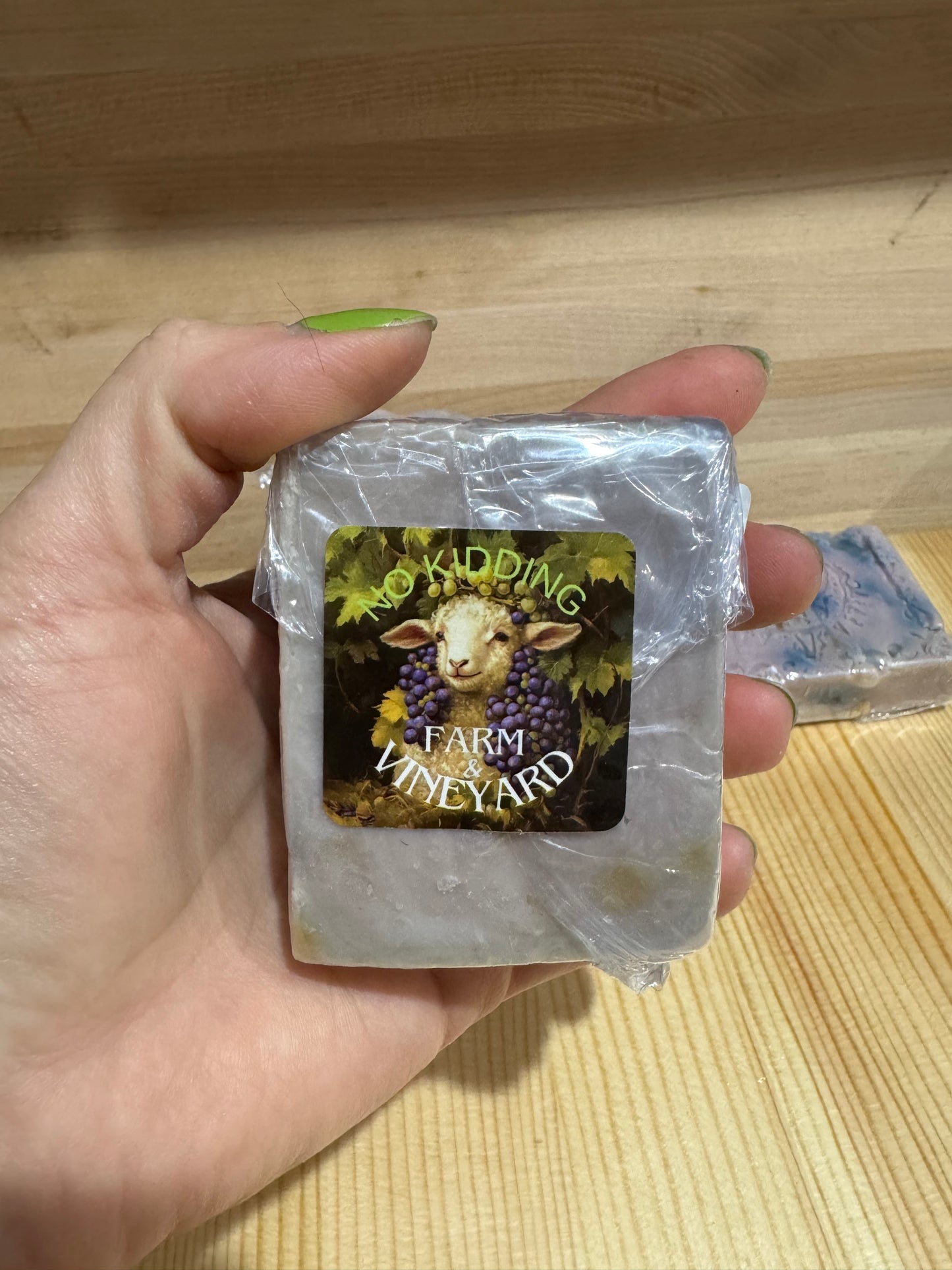 Hand holding a goat milk soap bar with No Kidding Farm and Vineyard logo 