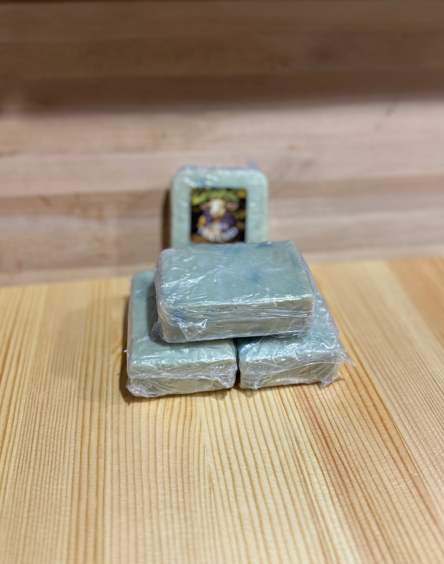 Stack of handmade green blue Sandalwood and Clary Sage goat milk soap bars with No Kidding Farm label.