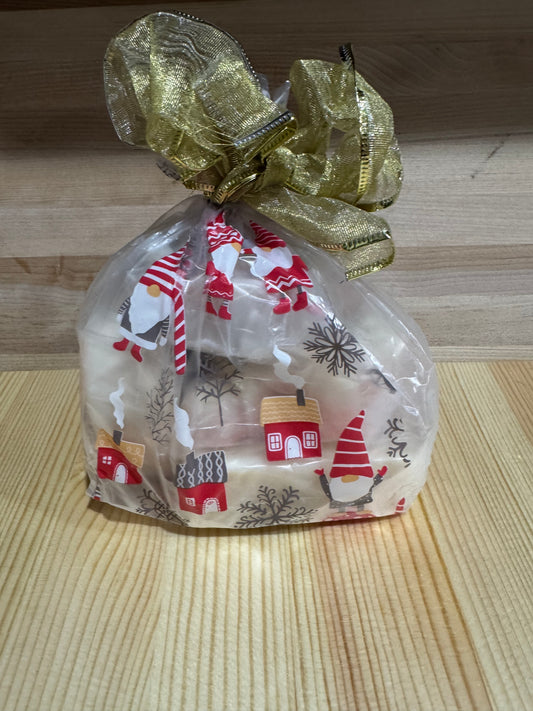 Festive holiday gift sack featuring gnomes and gold ribbon, filled with 5 handcrafted goat milk soap bars, sitting on wood table.