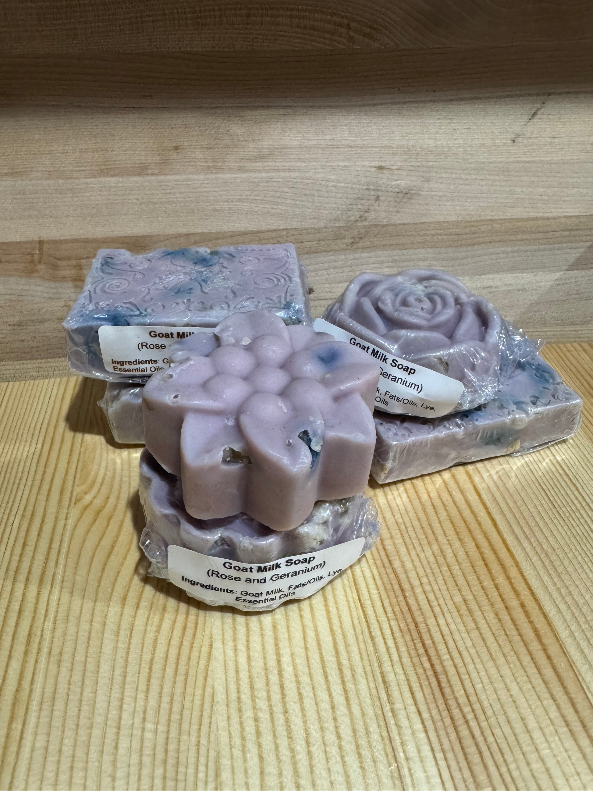 Goat milk floral soap bars with labels on a wooden surface