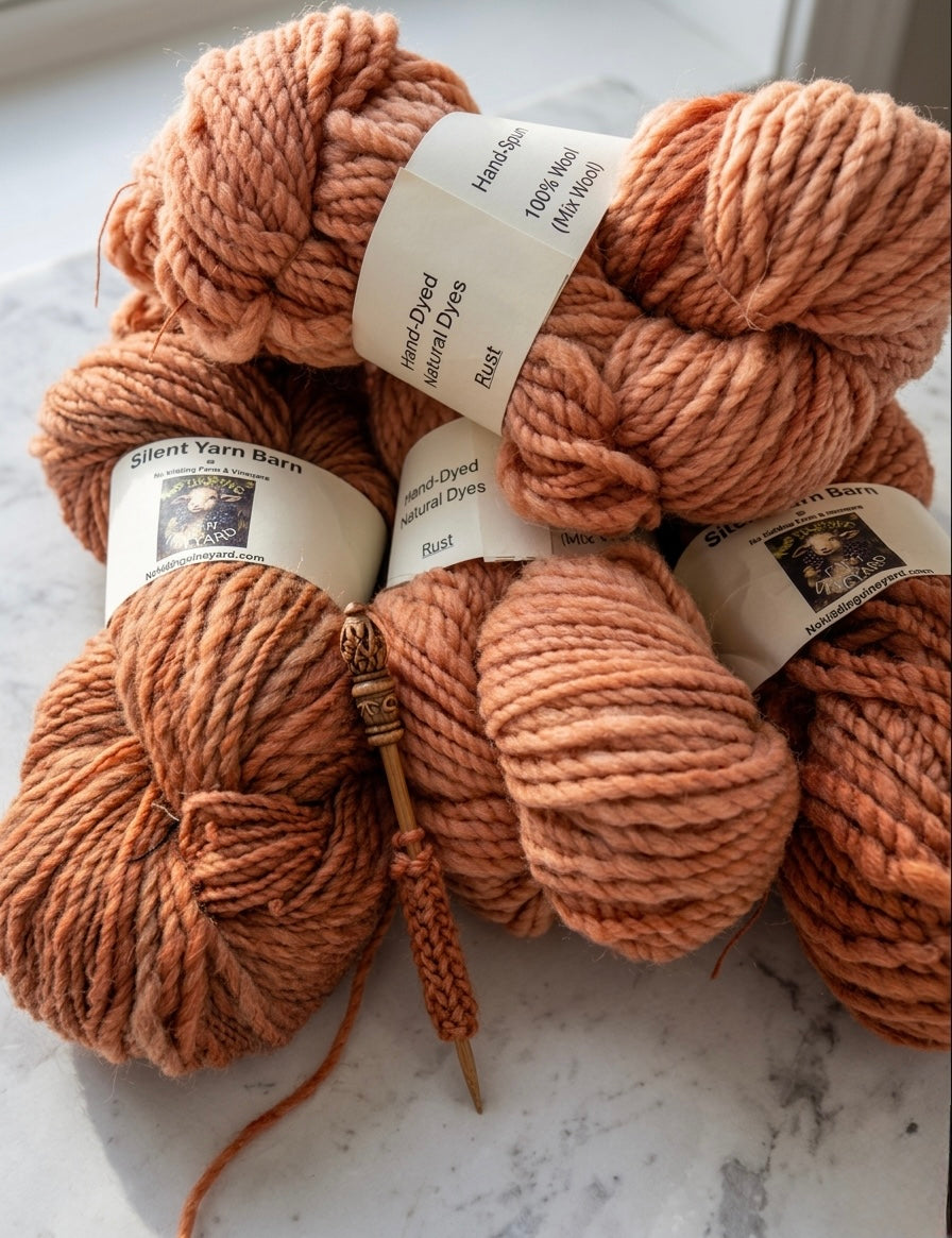 Three skeins of rust-colored yarn with labels on a marble surface