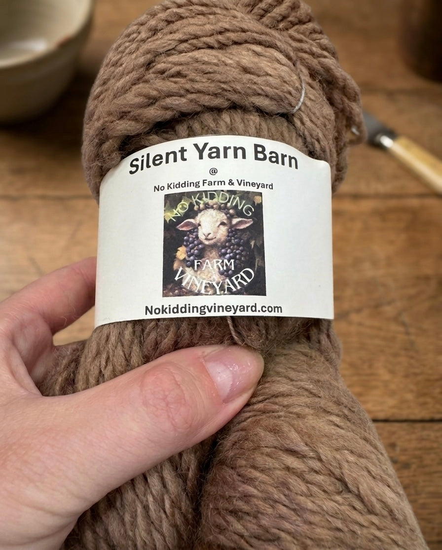 Brown skein of yarn with No Kidding Farm and Vineyard label