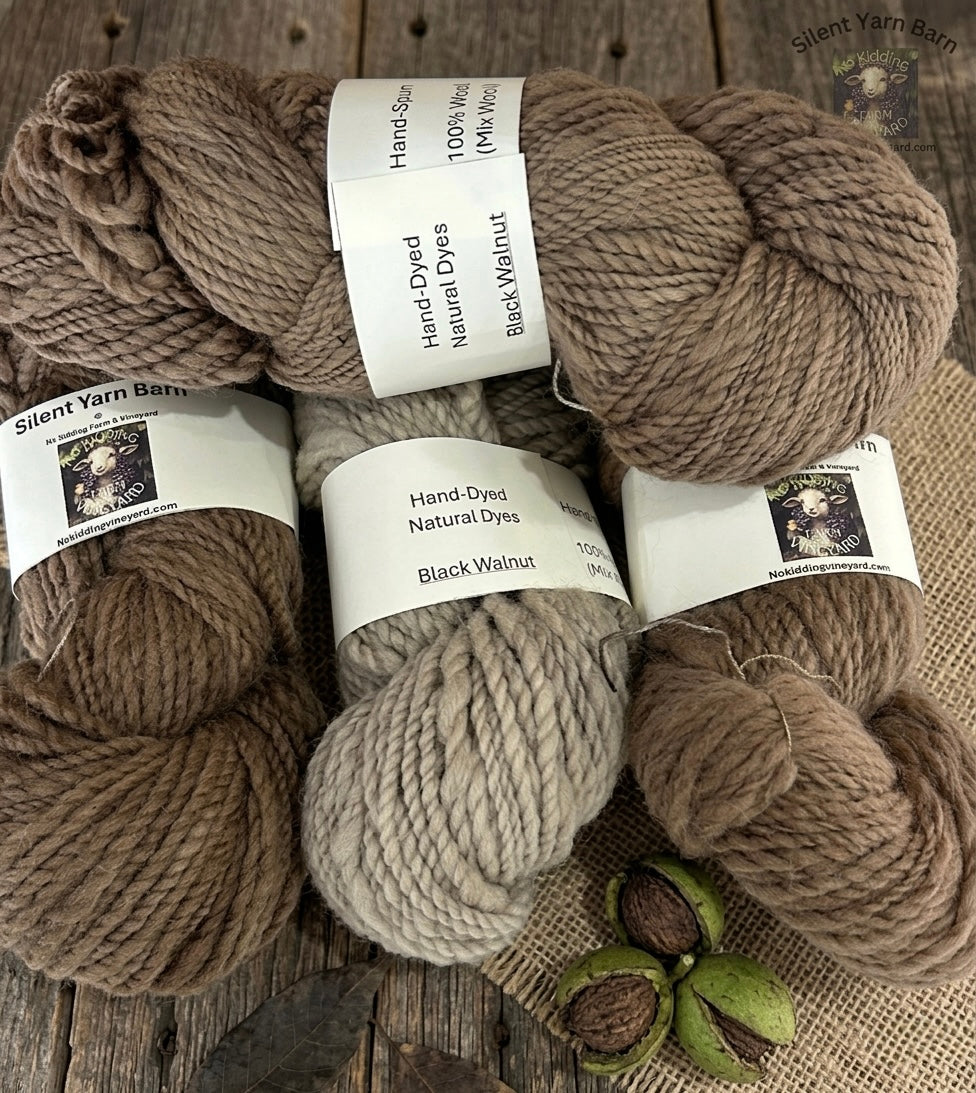 Five skeins of hand-dyed yarn in various shades on a wooden surface with No Kidding Farm and Vineyard branding.
