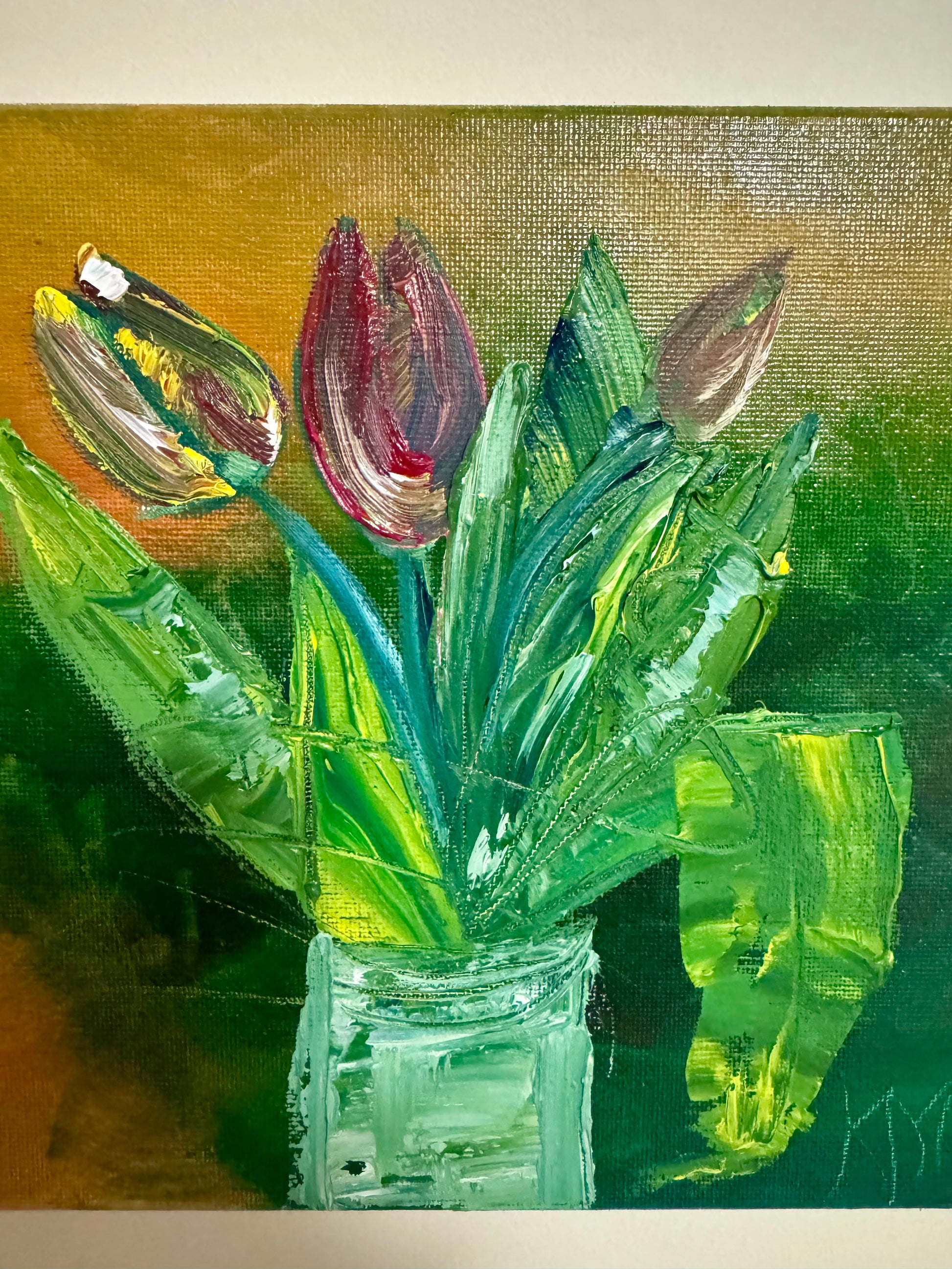 Impasto oil painting of red tulips in a glass jar with heavy texture, green leaves, and a gold-brown background on a tabletop easel.